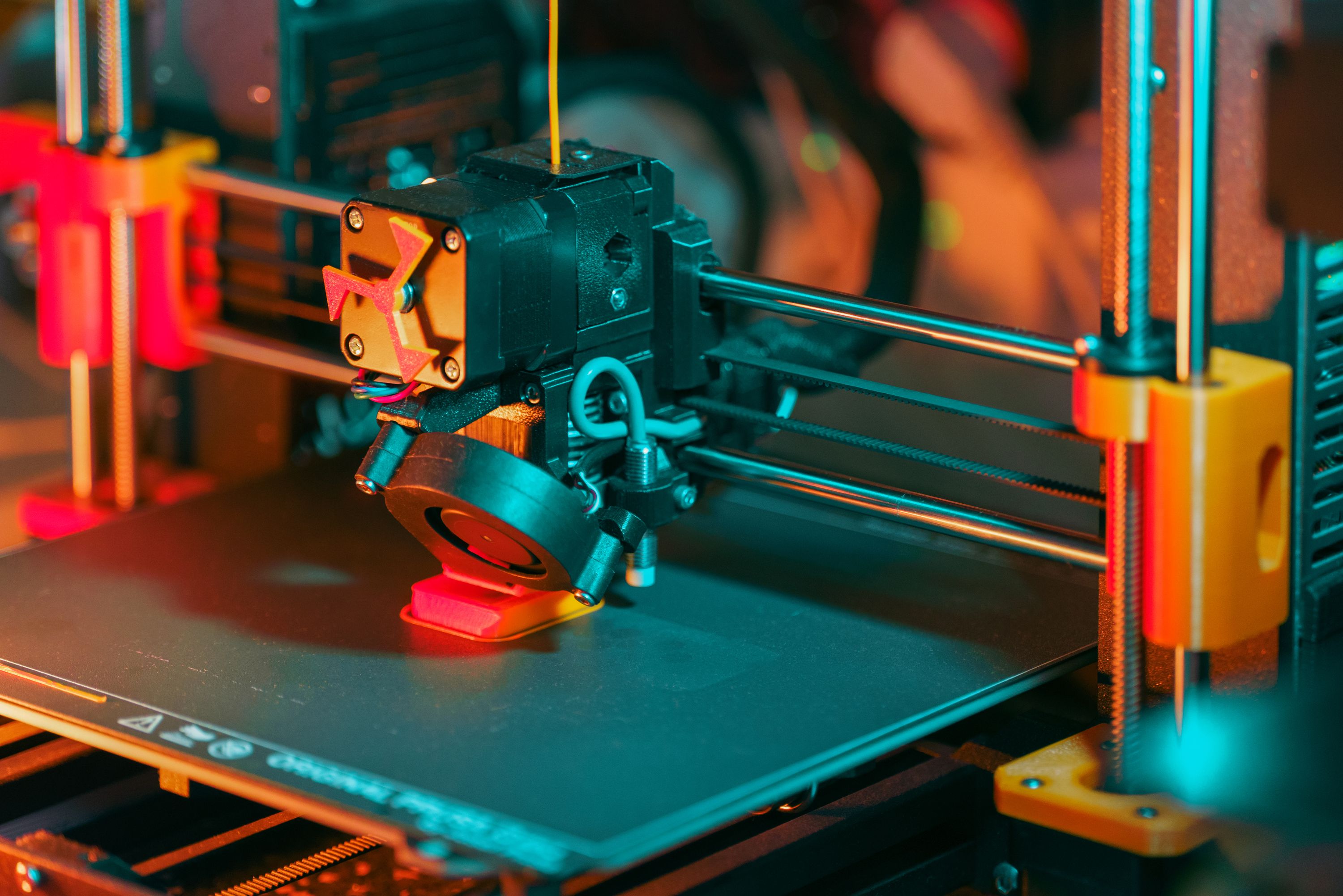 The print head of an FDM 3D printer partway through a job, filament feeding down into the nozzle.