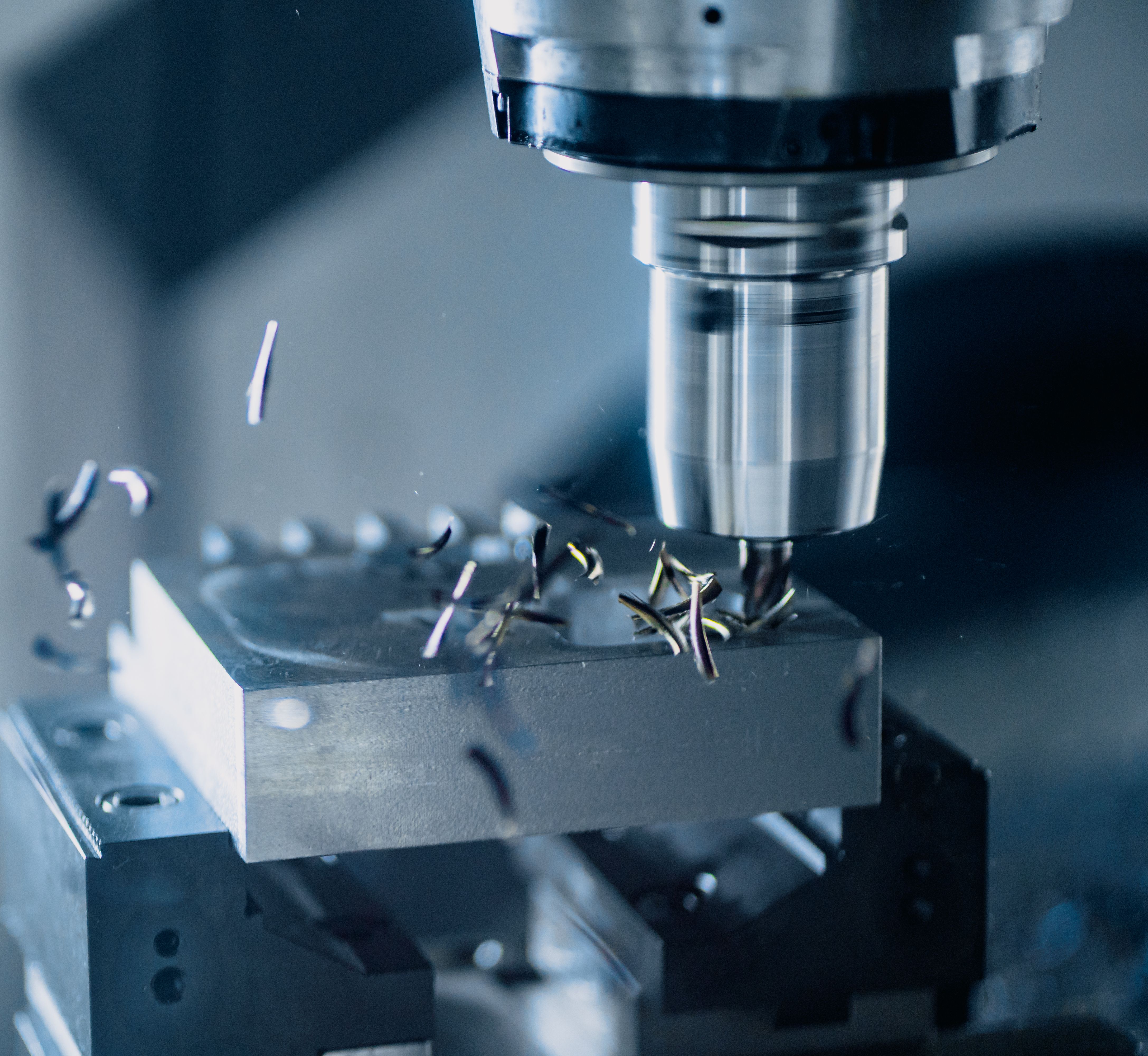 An end mill cutting a pocket into an aluminium block, swarf lifting away from the cutter.