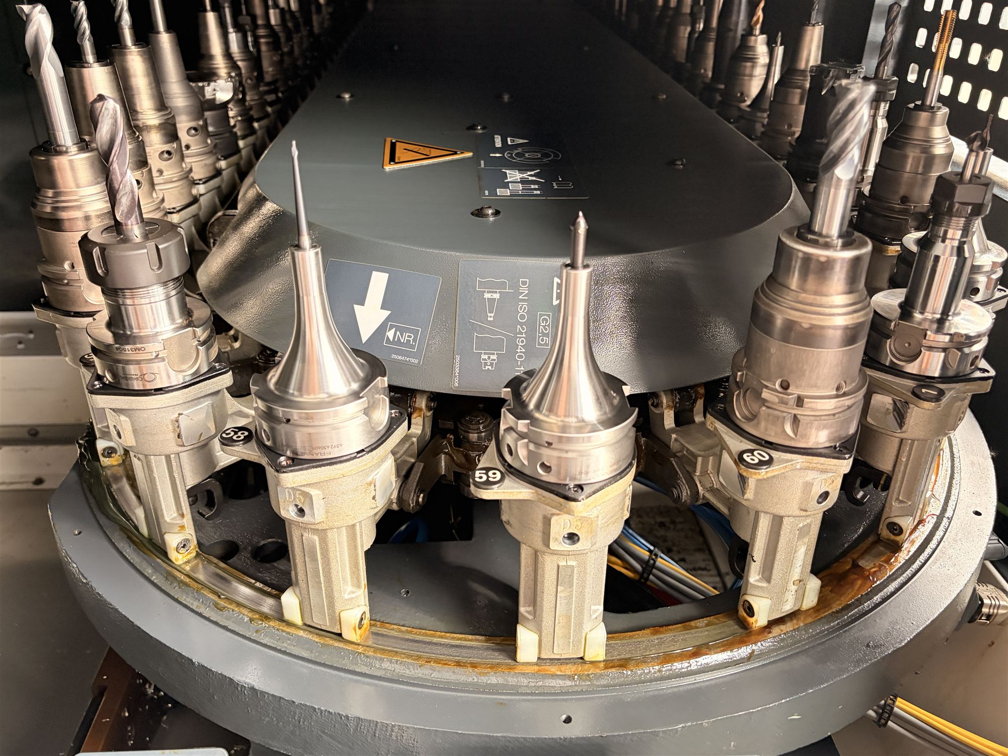The tool magazine inside the DMG MORI DMU 50, a ring of numbered toolholders loaded with drills and cutters.