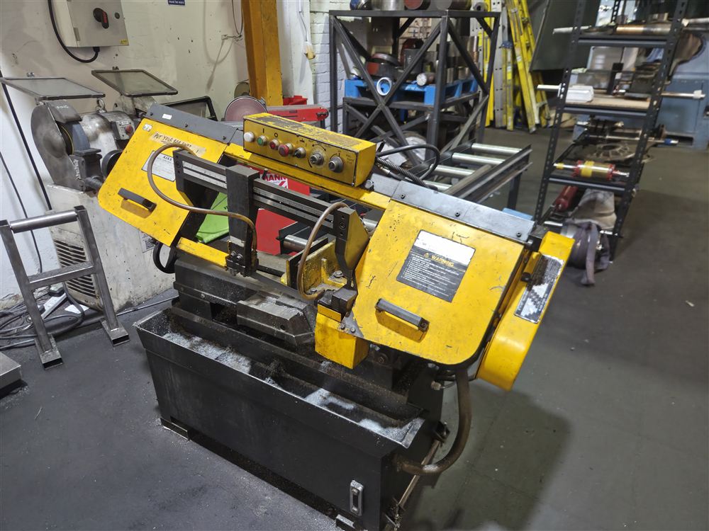 A yellow horizontal bandsaw on the workshop floor.
