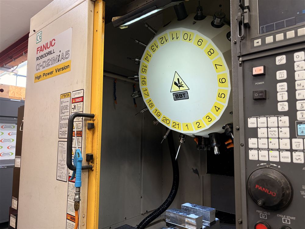 The FANUC Robodrill with its door open, showing the tool changer and a vice on the table.