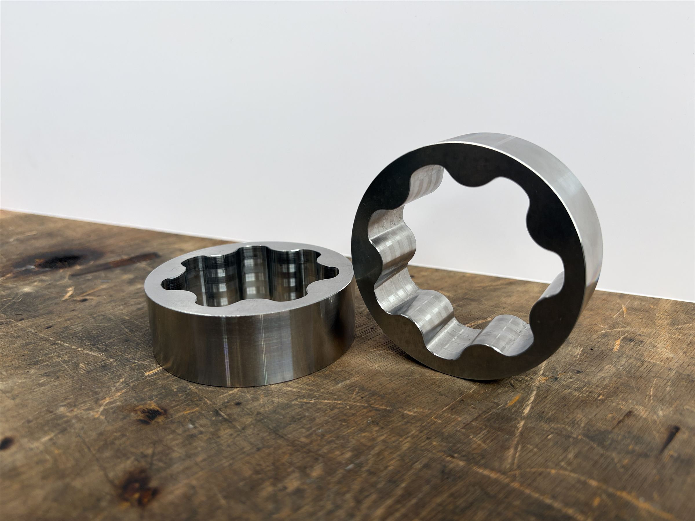 The matching outer rotors, one lying flat and one stood on its edge showing the lobed bore.